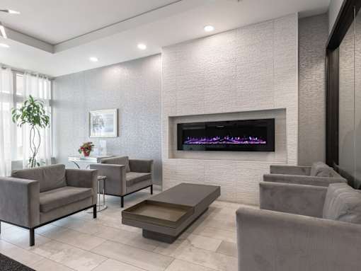 A modern living room with grey furniture and a purple lighted fireplace.