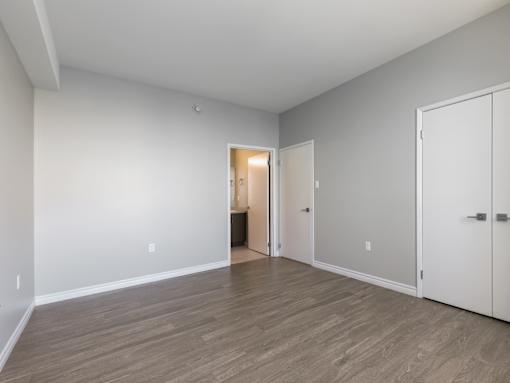 A room with a white door and a brown floor.
