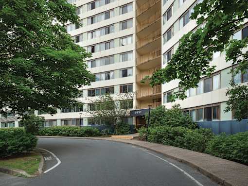A tall residential building with a curved driveway in front.