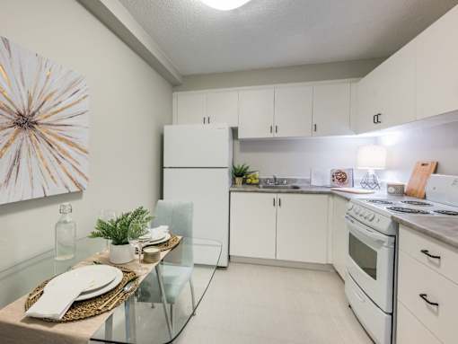 A modern kitchen with a glass table and white cabinets.