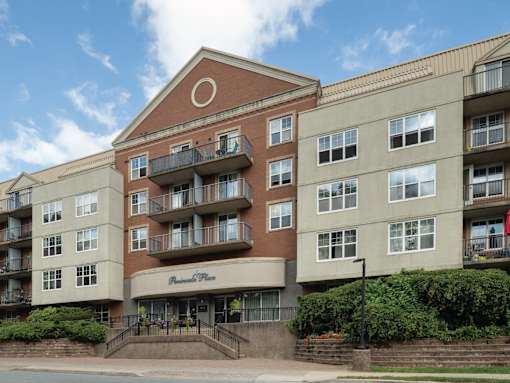 A large apartment building with a brown brick facade and a sign that says "Pinnacle Place.".