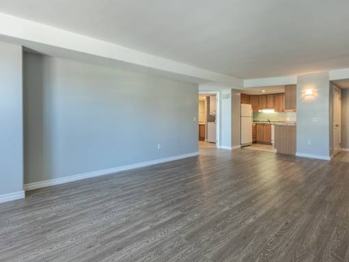A spacious room with wooden flooring and white walls.