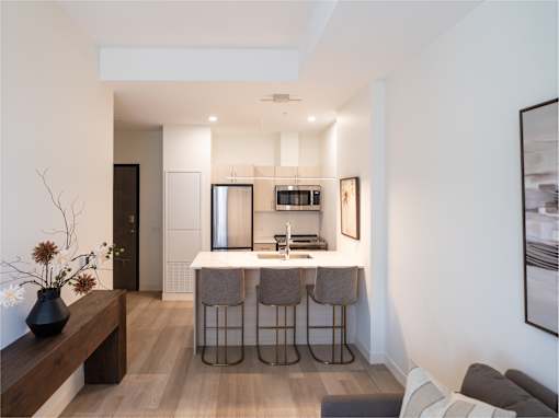 A modern kitchen with a bar stool and a dining table.
