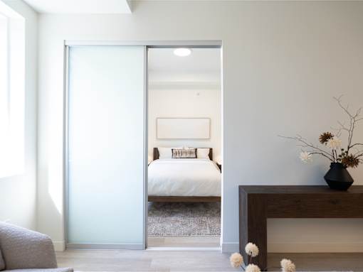 A bedroom with a bed, nightstand, and a couch.
