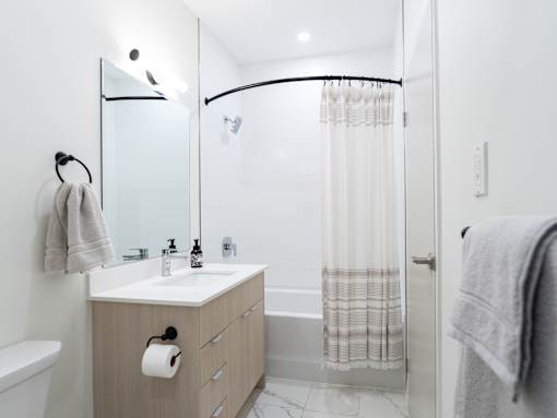 A bathroom with a white sink, a mirror, a towel rack, and a shower curtain.