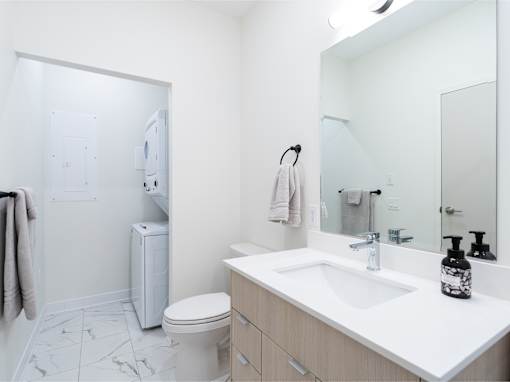 A white bathroom with a toilet, sink, and mirror.