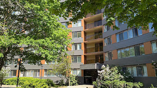 A modern apartment building with balconies and surrounded by greenery.