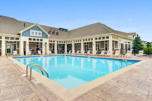 Luxury Apartments In Vernon Hills, IL - The Oaks of Vernon Hills - Resort-Style Swimming Pool With Lounge Chairs, And Resident Clubhouse In The Background