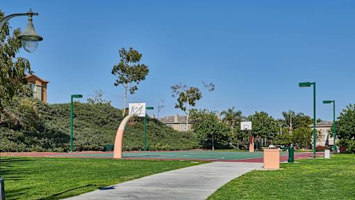 A park with a basketball court and a green lamp post.