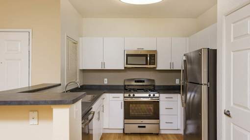 A kitchen with white cabinets and a black countertop.