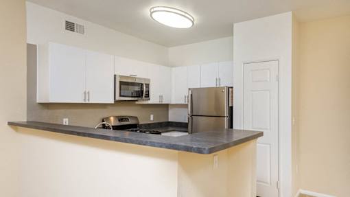 A kitchen with a stove, microwave, and refrigerator.