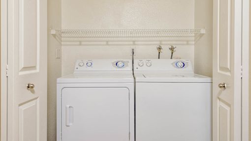 Two white front loading washing machines in a laundry room.