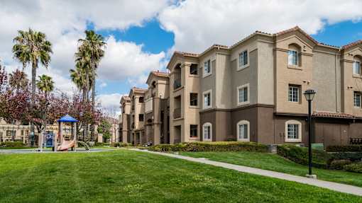 A row of apartment buildings with a playground in the foreground.