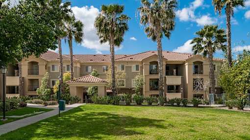 A building with a red tile roof and palm trees in front.