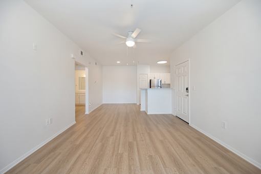 A long, empty room with wooden floors and white walls.
