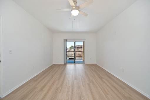 A room with a ceiling fan and wooden flooring.
