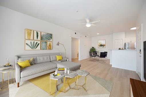 Model living room at Teresina Apartments in Chula Vista, CA, featuring wood grain floor paneling and a grey couch.