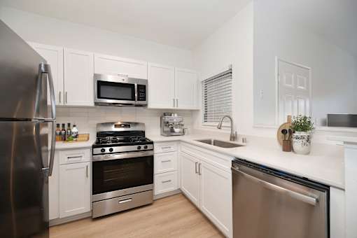 Model kitchen at Teresina Apartments in Chula Vista, CA, featuring stainless steel appliances and wood grain flooring.