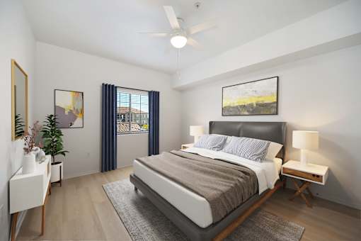 A bedroom with a large bed, a ceiling fan, and a painting on the wall.