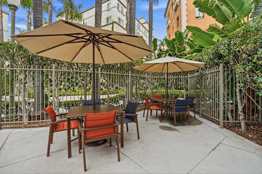 A patio with a table and chairs under umbrellas.