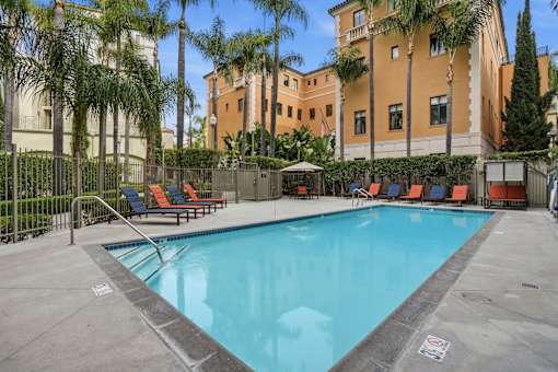 A pool surrounded by palm trees and lounge chairs.