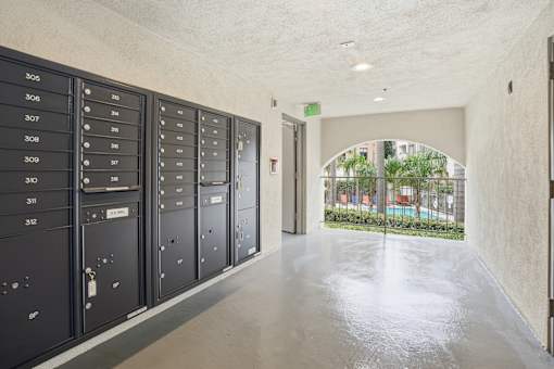 A hallway with a row of lockers on the left and a doorway leading to a balcony on the right.
