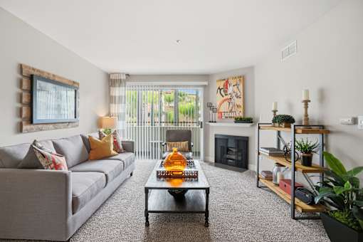 A living room with a grey couch, a coffee table, a fireplace, and a painting on the wall.