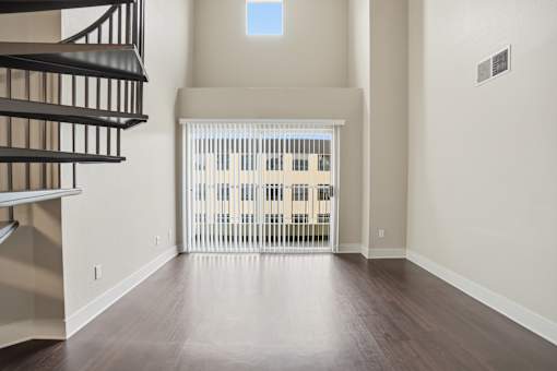 A room with a wooden floor and a balcony with a railing.
