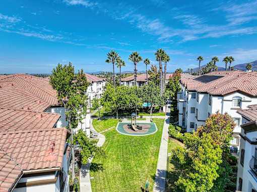 The grounds at Teresina Apartments in Chula Vista, CA, featuring a playground a view of the apartment exteriors.