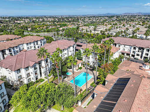 A large apartment complex with a swimming pool and palm trees.