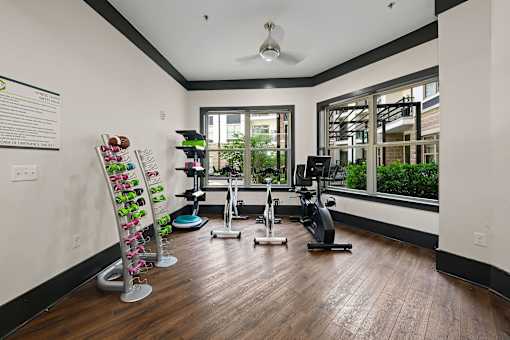 A gym room with a variety of equipment including a treadmill, stationary bike, and a rack of resistance bands.