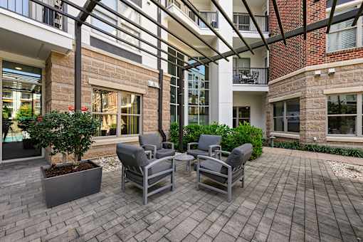 A patio with chairs and a table with a planter in front of a building.