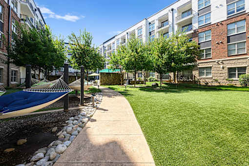 A sunny day at a residential area with a hammock and a well-maintained lawn.