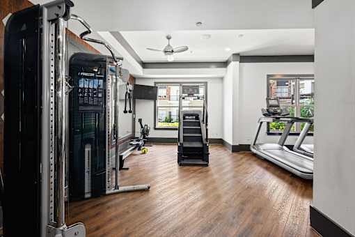 A gym with a row of treadmills and a row of weight machines.