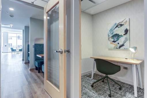 a home office with a desk and a door to a living room