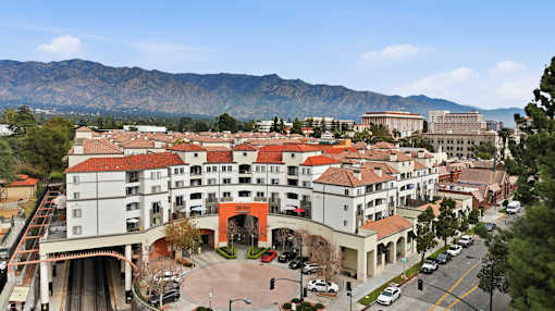 A large white building with a red roof is surrounded by mountains.
