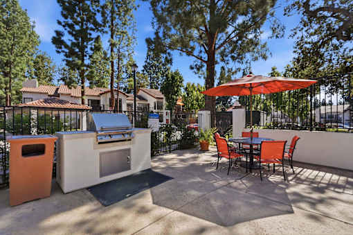 A patio with a table, chairs, and an umbrella.
