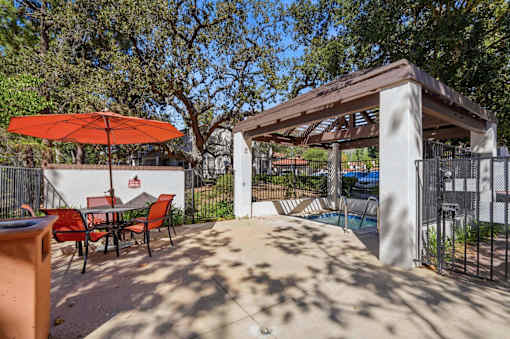 A patio with a table and chairs under a red umbrella.