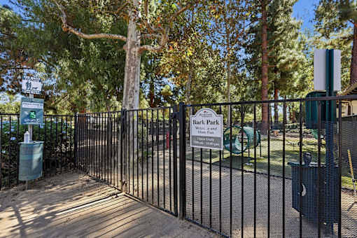 A black metal fence surrounds a green sign that says Bark Park.