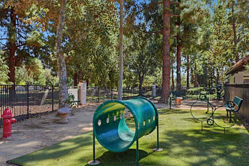 A playground with a green slide and a red fire hydrant.