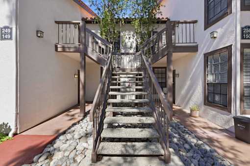 A staircase with a railing leads up to a balcony.