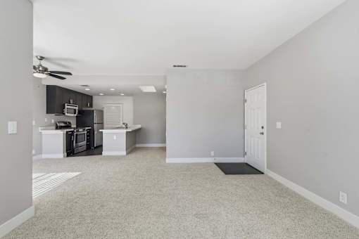 A spacious kitchen with white appliances and a ceiling fan.