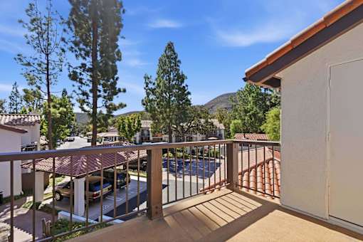 A balcony with a pool and trees in the background.