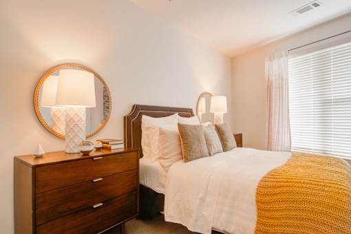 A bedroom with a bed, nightstand, and lamp.