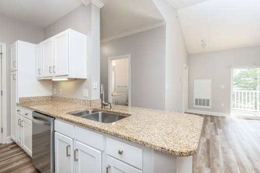 A kitchen with white cabinets and a granite countertop.