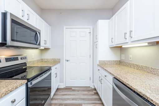 A kitchen with white cabinets and granite countertops.