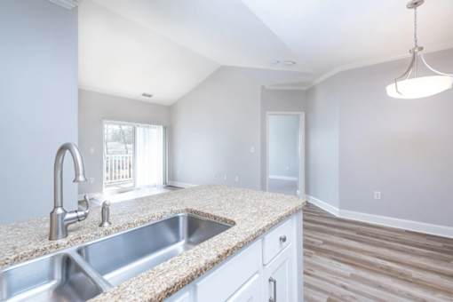 A kitchen with a granite countertop and stainless steel sink.