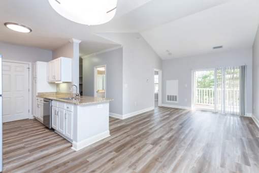 A spacious kitchen with white cabinets and a wooden floor.