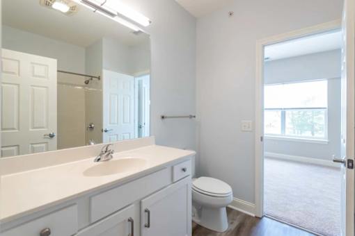 A white bathroom with a toilet, sink, and mirror.