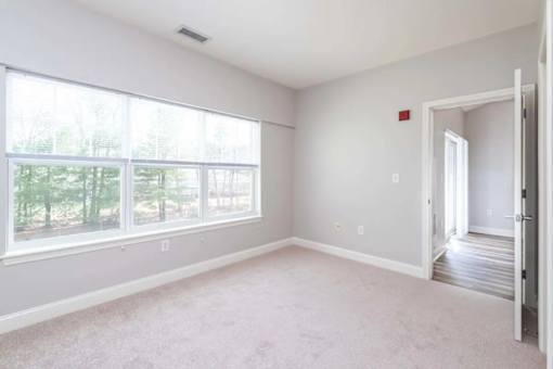 A room with a carpeted floor and a large window.